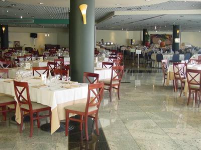 Velký banketový sál s prostřenými stoly a červenými dřevěnými židlemi v hotelu.