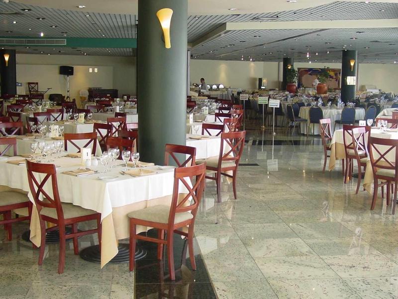 Velký banketový sál s prostřenými stoly a červenými dřevěnými židlemi v hotelu.