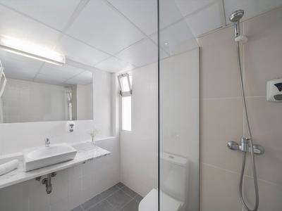 Světlá, moderní koupelna s umyvadlem, toaletou, zrcadlem a sprchou s skleněnou přepážkou.