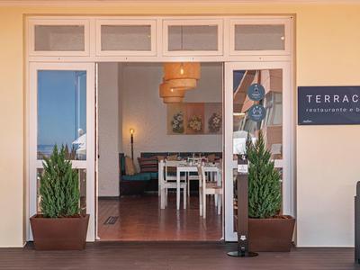 Vstup na terasu s dvěma rostlinami a cedulí vedle dveří.