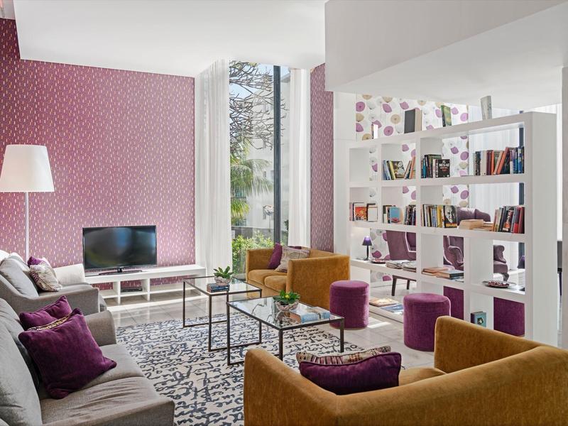 Světý obývací pokoj s pohodlnými křesly, pohovkou, knihovnou a velkým oknem s výhledem.