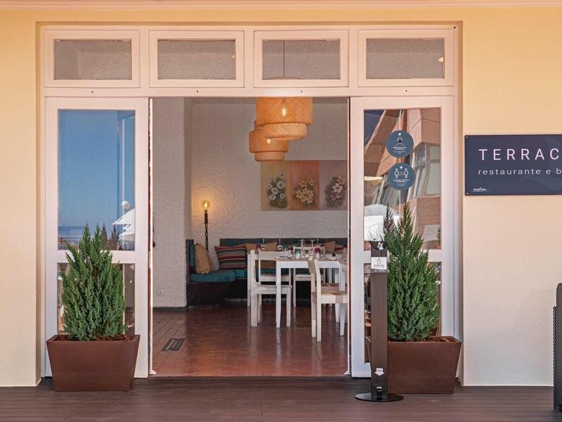 Vstup na terasu s dvěma rostlinami a cedulí vedle dveří.