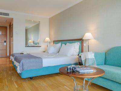 Modern eingerichtetes Hotelzimmer mit Doppelbett, Sofa und Holzboden.