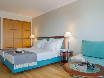 Modernes Hotelzimmer mit Doppelbett, Holzboden und Sitzbereich mit Tisch und Stuhl.