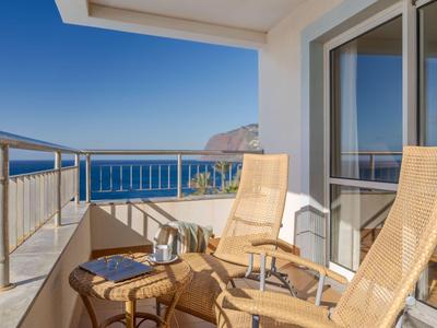 Balkon mit zwei Holzstühlen und Meerblick eines Hotels an der Küste.