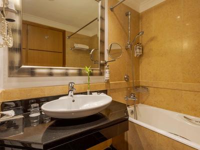 Moderner Hotelbadezimmer mit Waschbecken, großem Spiegel und Badewanne mit Duschvorrichtung.