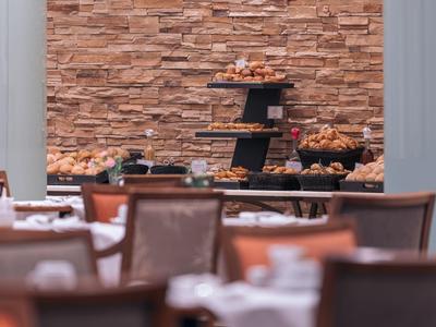 Hotelrestaurant mit gedeckten Tischen und Buffet vor einer Steinwand.