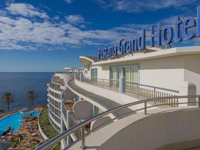 Blick auf ein modernes Grand Hotel mit Balkon, Pool und Meer im Hintergrund.