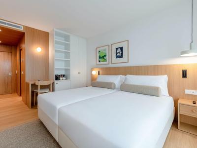 Moderne hotelkamer met twee bedden, houten meubels en minimalistische inrichting.