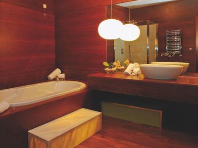 Modernes Badezimmer mit Holzvertäfelung, großer Badewanne, Waschbecken und zwei runden Hängelampen.
