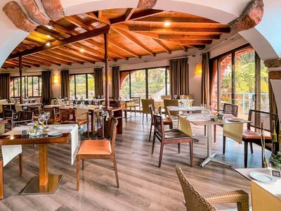 Gemütliches Restaurant mit Holzbalken, großen Fenstern und modern eingerichteten Tischen und Stühlen.