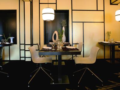 Ein modernes Restaurant mit schwarzen Tischen, hellen Stühlen und stilvoller Wandgestaltung.