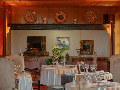 Przytulna jadalnia z okrągłymi stołami, białymi obrusami i wygodnymi fotelami