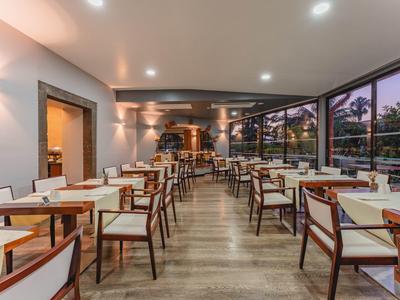 Nowoczesna, jasna jadalnia z drewnianymi krzesłami i dużymi oknami.