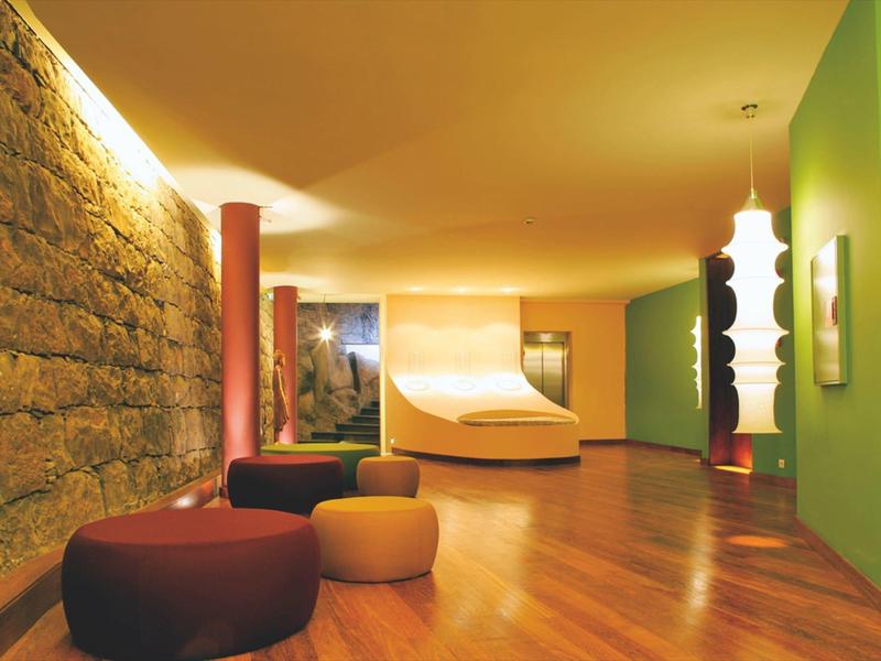 Nowoczesne lobby hotelowe z kamienną ścianą, kolorowymi siedzeniami i drewnianą podłogą.