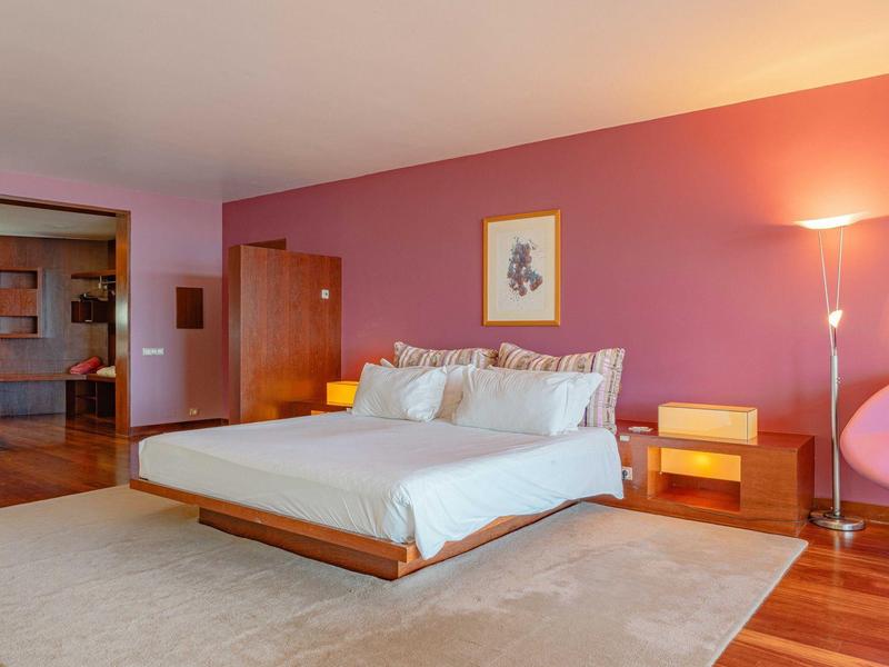 Nowoczesna sypialnia z dużym łóżkiem, drewnianymi meblami i ciepłym oświetleniem w pokoju hotelowym.