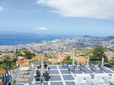 Vue sur une ville côtière avec mobilier de terrasse sur une terrasse sur le toit et la mer en arrière-plan.