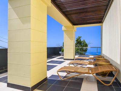 Balcon avec chaises longues et vue sur la mer sous un plafond en bois dans un hôtel
