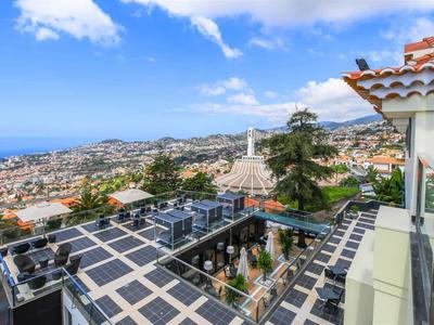 Balcon avec garde-corps en verre offrant une vue panoramique sur la ville et la mer sous un ciel bleu.