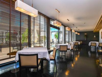 Salle à manger d'hôtel moderne avec grandes fenêtres et tables dressées.