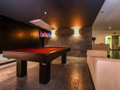 Salle de jeux moderne avec table de billard, coin salon et éclairage d'ambiance.