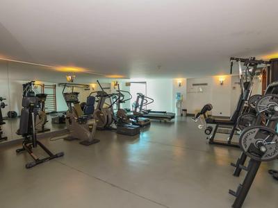 Modern gym with various exercise machines and a large wall mirror.