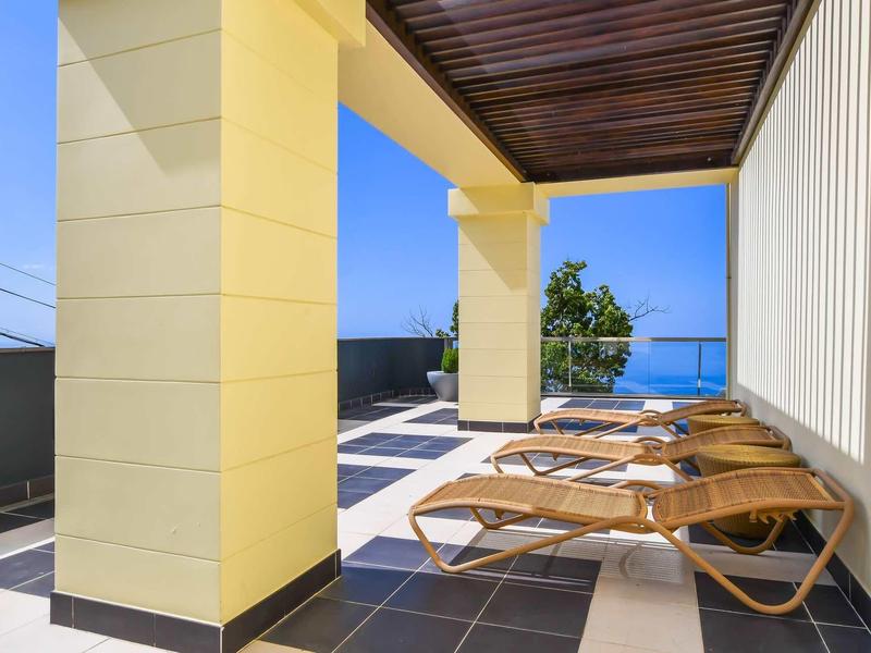 Balcon avec chaises longues et vue sur la mer sous un plafond en bois dans un hôtel