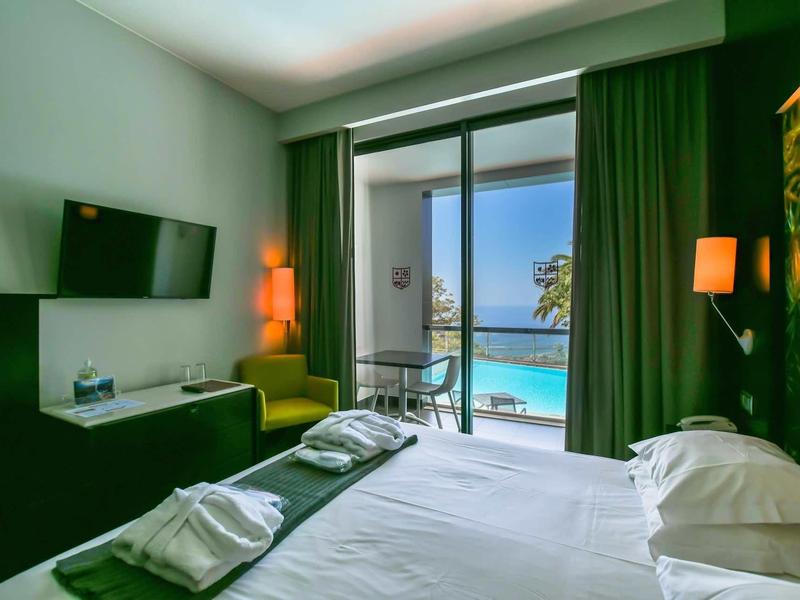 Chambre d'hôtel moderne avec lit double, balcon et vue sur la piscine.