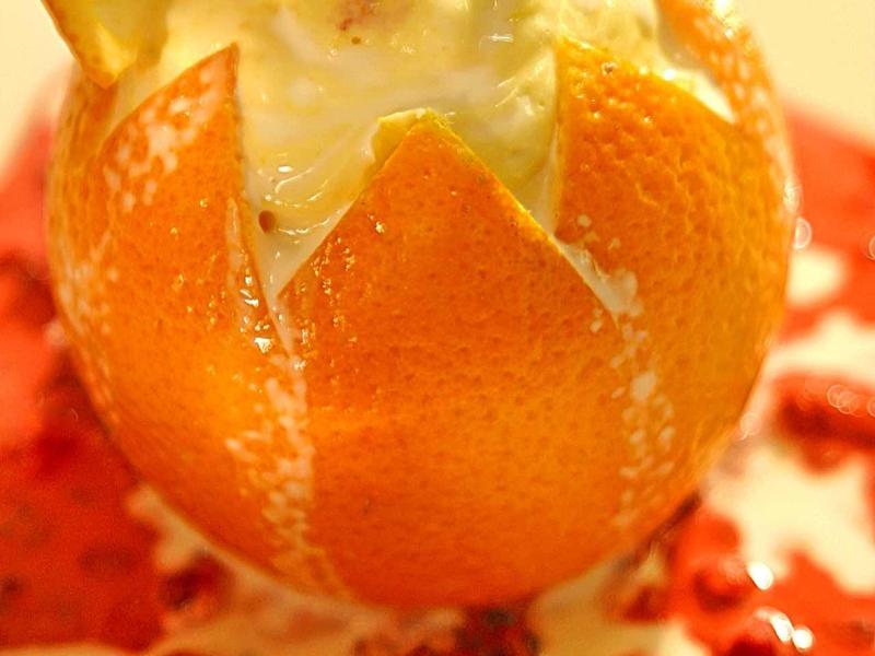 Dessert à l'orange avec glace, feuille de menthe et garniture de baies sur sauce aux fruits rouges.