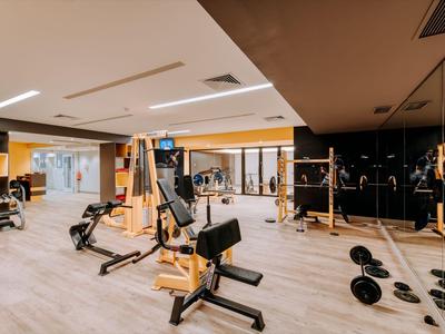 Modern gym with various strength training equipment and dumbbells in a hotel.
