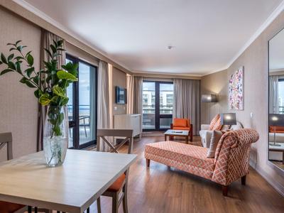 Modern living area with sofa, dining table, TV, and balcony with outdoor view.