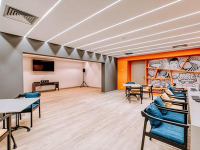 Modern conference room with wooden flooring, blue chairs, and orange wall design