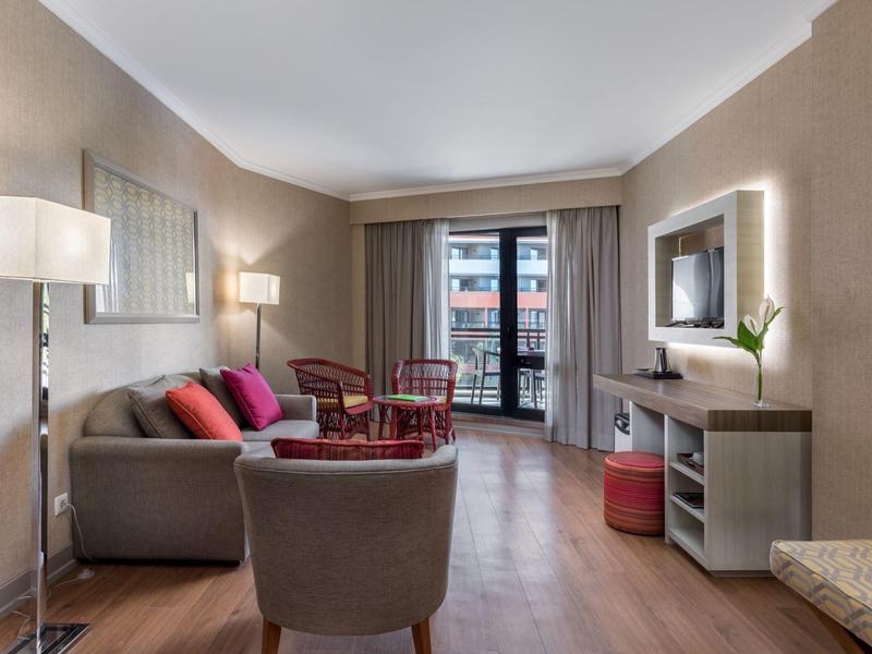 Modern living room with sofa, armchairs, and access to a balcony.