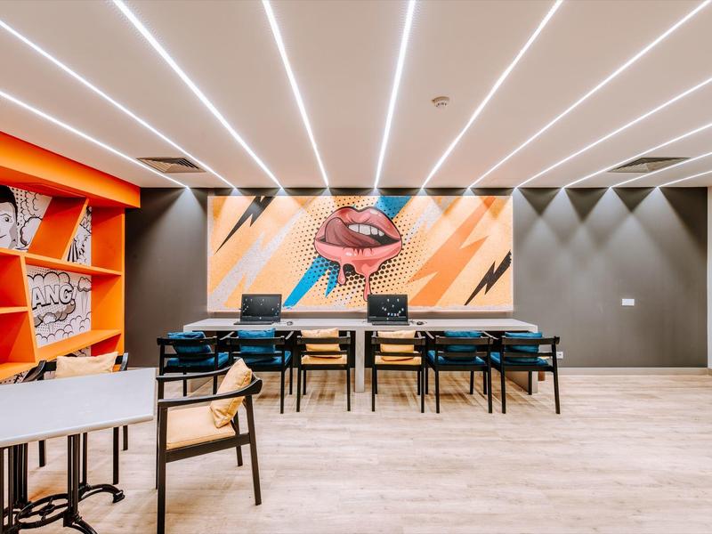 Modern meeting room with colorful artwork and multiple tables and chairs.