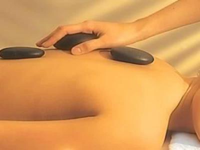 Donna si rilassa durante un massaggio con pietre calde su un lettino da massaggio.