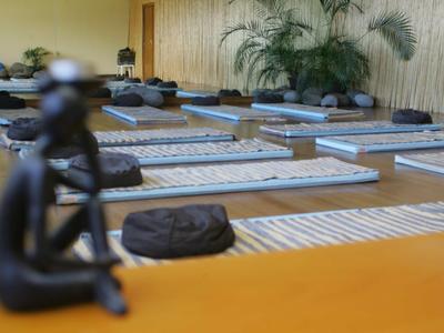 Sala yoga tranquilla con materassini, cuscini e decorazioni scultoree in un'atmosfera rilassata.