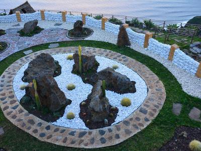 Un giardino zen con pietre, ghiaia e vista sul mare sullo sfondo.