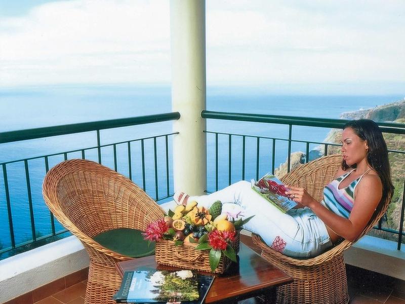 Donna che si rilassa sul balcone con vista mare su una sedia di vimini in una giornata di sole