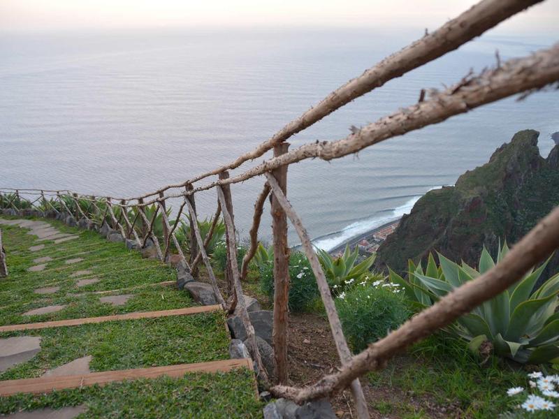 Scale di pietra con corrimano in corda scendono una costa ripida verso il mare.
