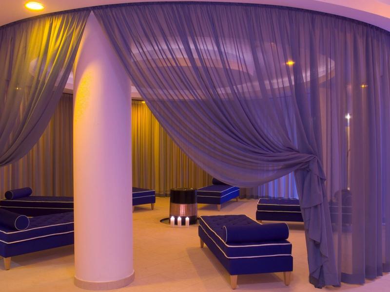 Ein stilvoller Ruhebereich mit blauen Sesseln, weißen Säulen und durchsichtigen blauen Vorhängen.
