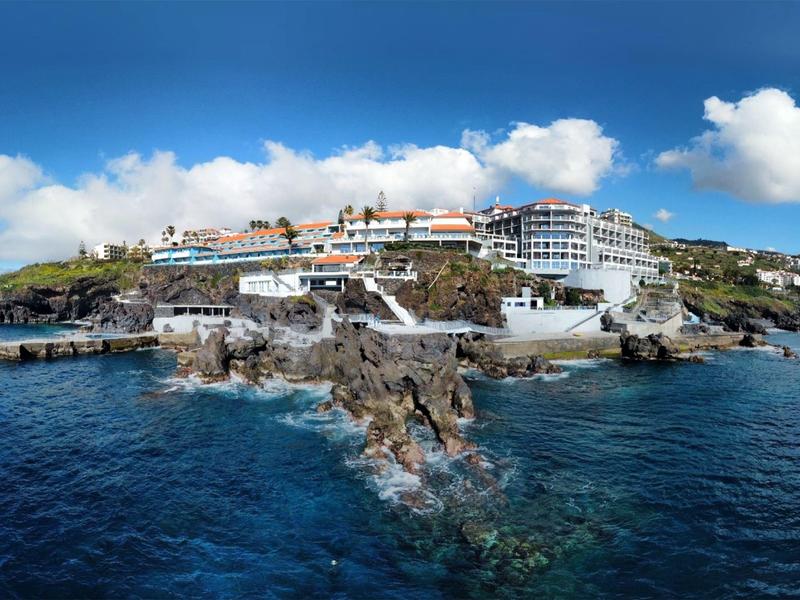 Ośrodek hotelowy na skalistym wybrzeżu z czystym, niebieskim morzem i pochmurnym niebem