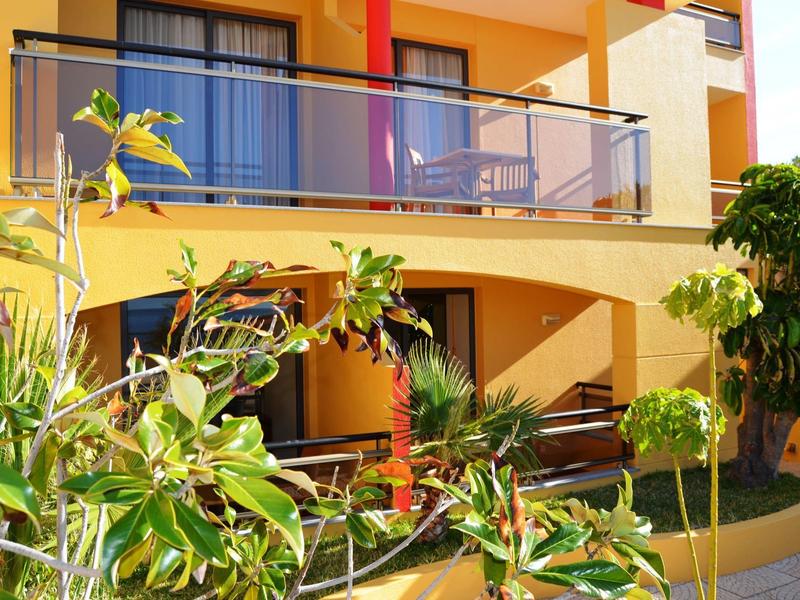 Balkon hotelowy ze szklaną balustradą i zielonymi roślinami na pierwszym planie.