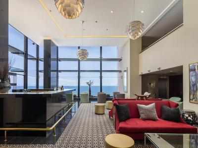 Espace lounge d'hôtel moderne avec de grandes fenêtres donnant sur la mer.