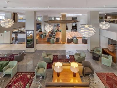 Hall d'hôtel moderne avec espaces de sièges, tapis et éclairage chaleureux.