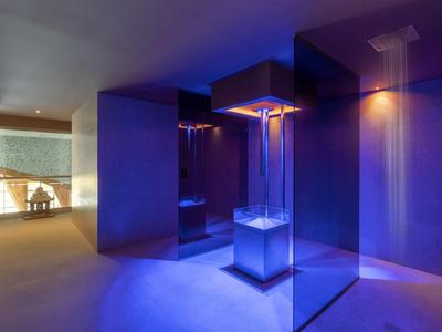 Salle de bain moderne avec tour de douche illuminée et éclairage d'ambiance bleu.