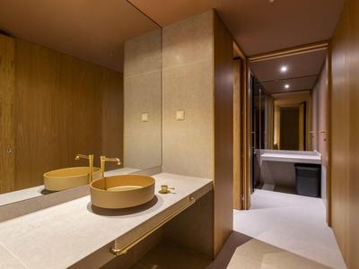 Salle de bain moderne avec lavabo rond, robinet doré et grand mur miroir.