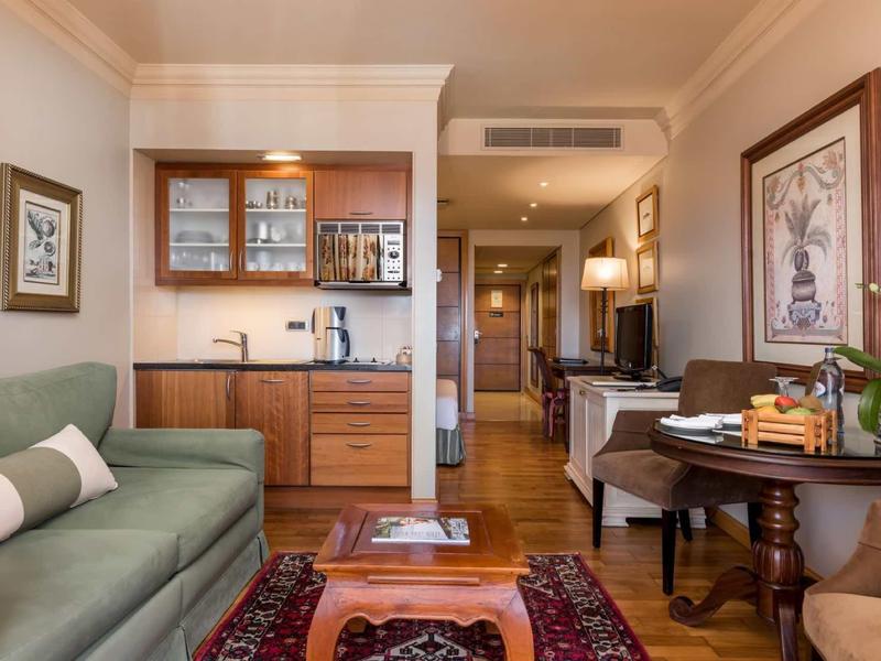 Salon d'hôtel confortable avec canapé, meubles en bois et tapis aux tons chauds.