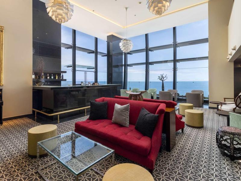 Espace lounge moderne avec grandes fenêtres et vue sur la mer dans un hôtel.