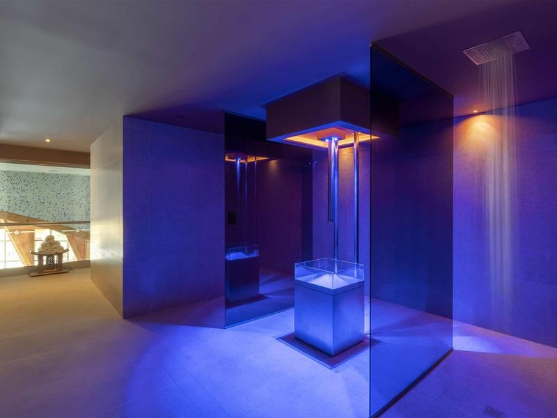 Salle de bain moderne avec tour de douche illuminée et éclairage d'ambiance bleu.