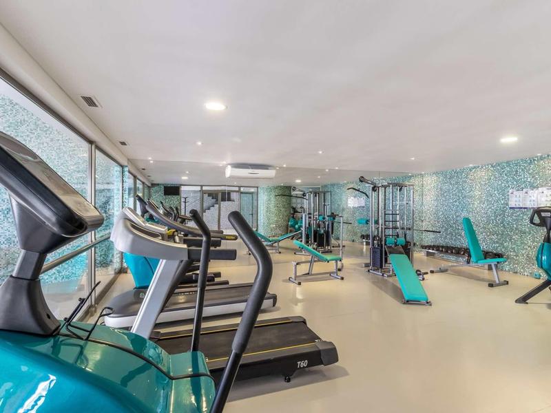 Salle de sport moderne avec équipements d'exercice et design lumineux dans un hôtel.
